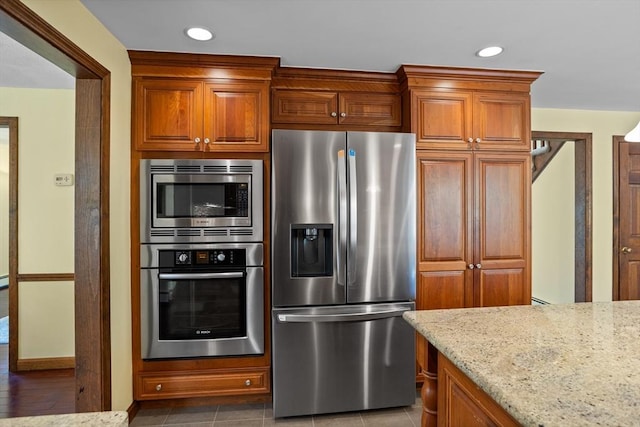 kitchen featuring stainless steel appliances, light stone countertops, brown cabinetry, and recessed lighting