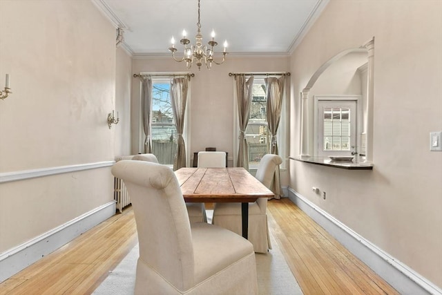 dining space featuring crown molding, light wood-type flooring, and a chandelier