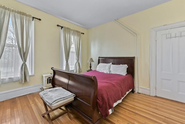 bedroom featuring wood-type flooring and a baseboard heating unit