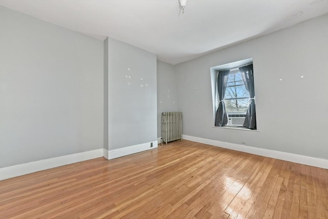 unfurnished room featuring light hardwood / wood-style flooring, radiator, and cooling unit