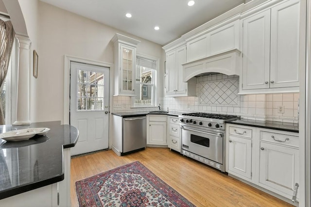 kitchen featuring sink, white cabinetry, light hardwood / wood-style floors, decorative columns, and stainless steel appliances