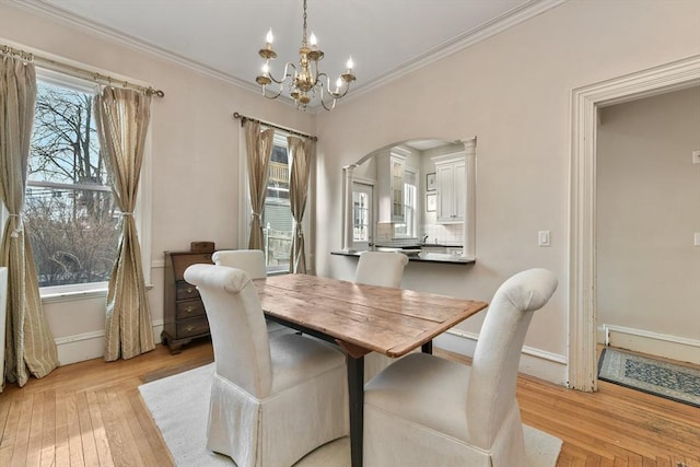 dining room featuring crown molding, light hardwood / wood-style floors, and a notable chandelier