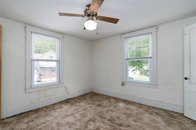 carpeted spare room featuring healthy amount of natural light, ceiling fan, and baseboards