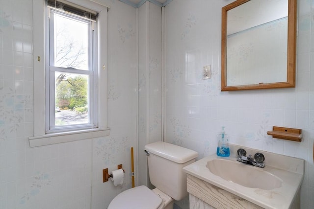 bathroom featuring a sink, healthy amount of natural light, tile walls, and toilet