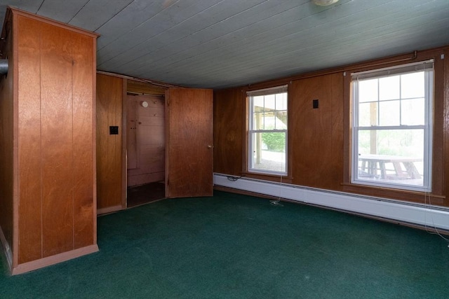 empty room with carpet flooring, a baseboard heating unit, wooden ceiling, and wood walls