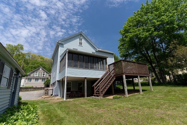 back of property with a sunroom, stairway, a deck, and a yard