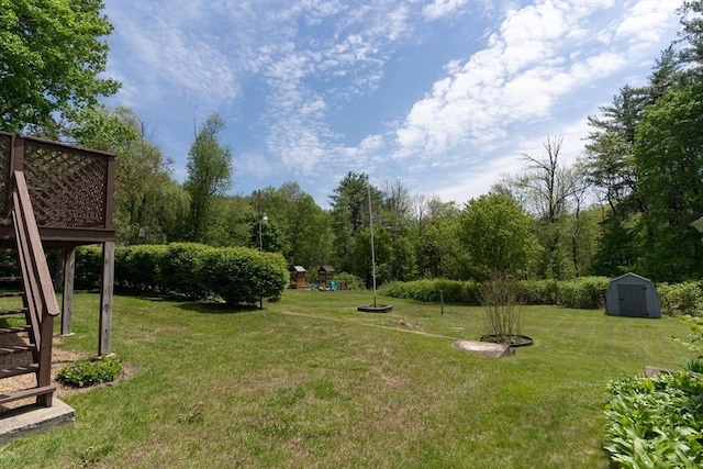 view of green lawn with stairs, a storage shed, an outbuilding, and a wooden deck