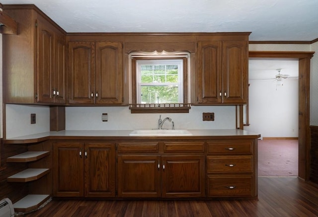 kitchen with a sink, dark wood-style flooring, light countertops, baseboard heating, and brown cabinetry