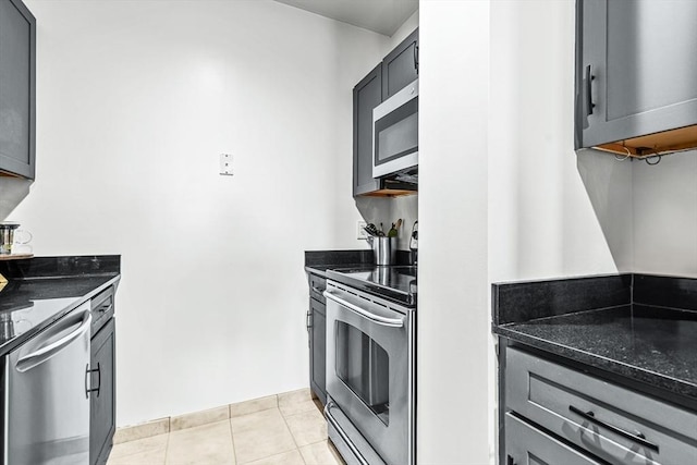 kitchen featuring dark stone counters, appliances with stainless steel finishes, light tile patterned floors, and gray cabinetry