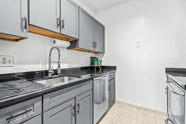 kitchen with a sink, dark stone counters, gray cabinets, and stainless steel appliances