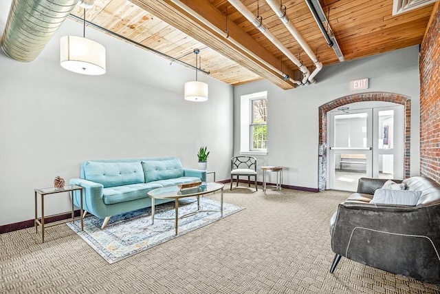 carpeted living area with baseboards, arched walkways, beamed ceiling, and wood ceiling