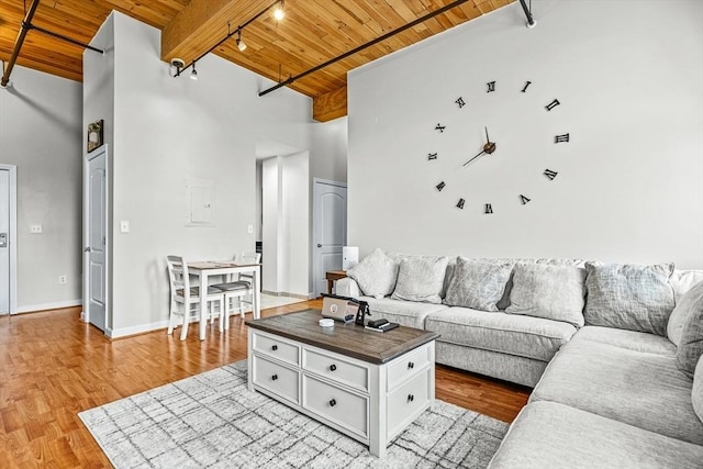 living area with light wood finished floors, a towering ceiling, wooden ceiling, and beamed ceiling