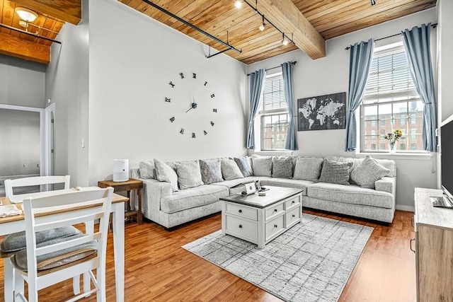 living area featuring beam ceiling, wooden ceiling, light wood-style flooring, and rail lighting
