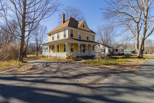 victorian home featuring a porch and a chimney