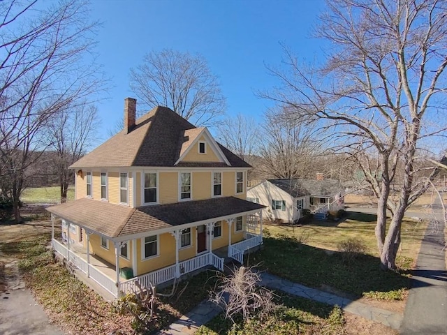 view of property exterior featuring covered porch, a chimney, a lawn, and a shingled roof