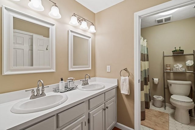 bathroom with toilet, vanity, and tile patterned flooring