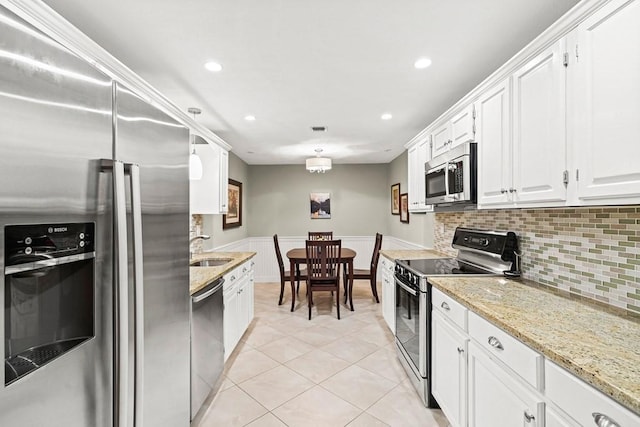 kitchen with light tile patterned floors, white cabinetry, appliances with stainless steel finishes, tasteful backsplash, and sink