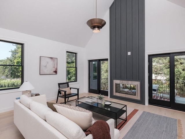 living room with light wood-type flooring, high vaulted ceiling, and a wealth of natural light