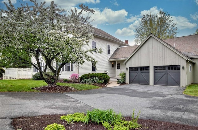 view of front of property with driveway, fence, a garage, a shingled roof, and a front yard