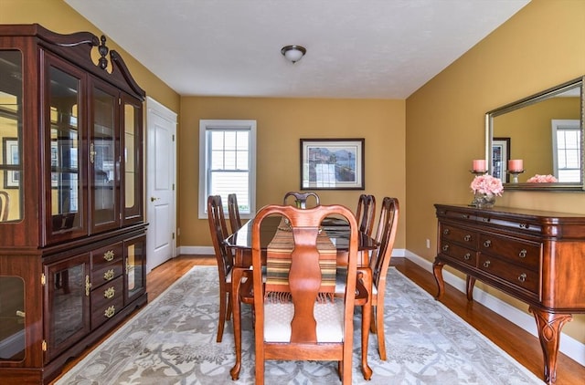 dining space featuring light wood-style floors, baseboards, and a healthy amount of sunlight