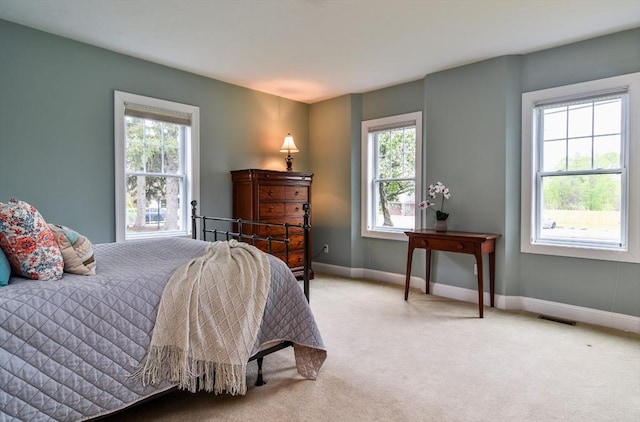 carpeted bedroom featuring baseboards, visible vents, and multiple windows