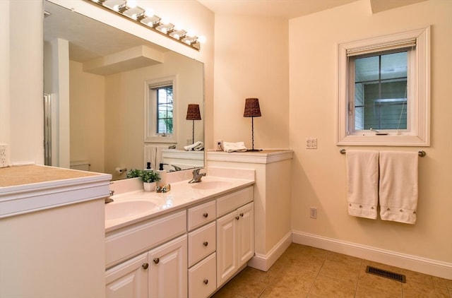 bathroom with double vanity, a sink, visible vents, baseboards, and tile patterned flooring