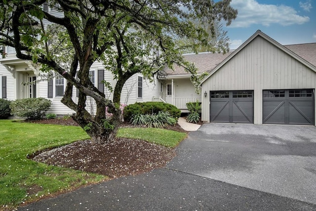 view of front of home with a front lawn, roof with shingles, a garage, and aphalt driveway