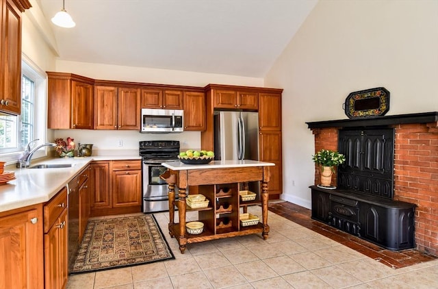 kitchen featuring light countertops, appliances with stainless steel finishes, brown cabinetry, and a sink