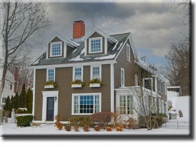 view of front facade with a chimney and fence