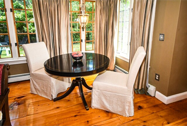 dining area with a wealth of natural light, light hardwood / wood-style flooring, and baseboard heating