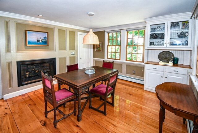 dining area featuring a baseboard radiator, crown molding, and light hardwood / wood-style flooring