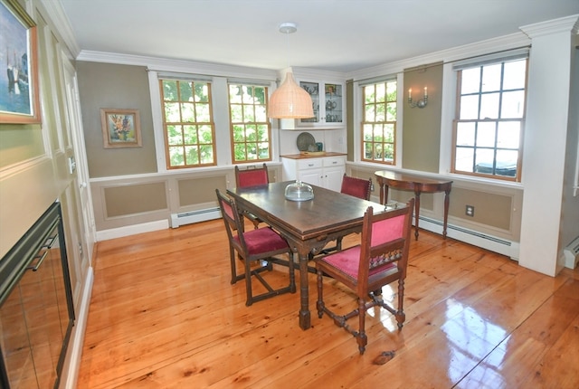 dining area with a baseboard radiator, ornamental molding, and light wood-type flooring