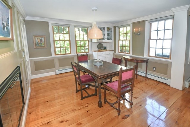 dining area with a decorative wall, crown molding, light wood-style floors, and baseboard heating