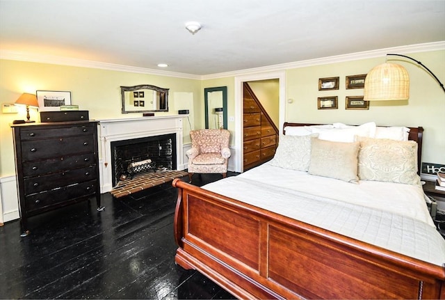 bedroom with ornamental molding, a fireplace, and dark wood finished floors