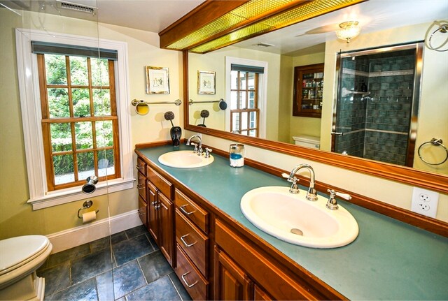 bathroom featuring tiled shower, toilet, and vanity