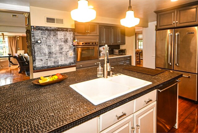 kitchen featuring hanging light fixtures, stainless steel appliances, sink, and dark hardwood / wood-style flooring