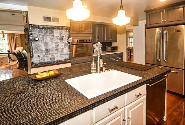 kitchen featuring hanging light fixtures, a sink, dark countertops, visible vents, and appliances with stainless steel finishes