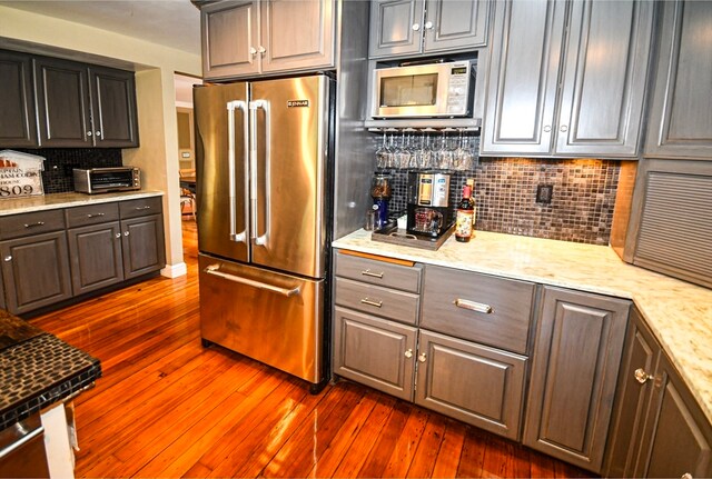 kitchen featuring stainless steel appliances, decorative backsplash, and dark hardwood / wood-style floors