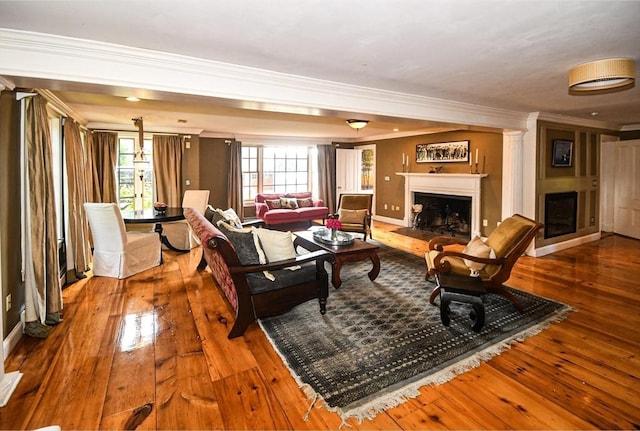 living area featuring baseboards, a fireplace, ornamental molding, and hardwood / wood-style flooring