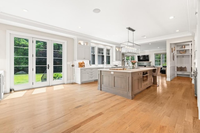 382 Lee St, Brookline, MA 02445 - kitchen with ornamental molding, light countertops, light wood finished floors, a kitchen island with sink, and glass insert cabinets