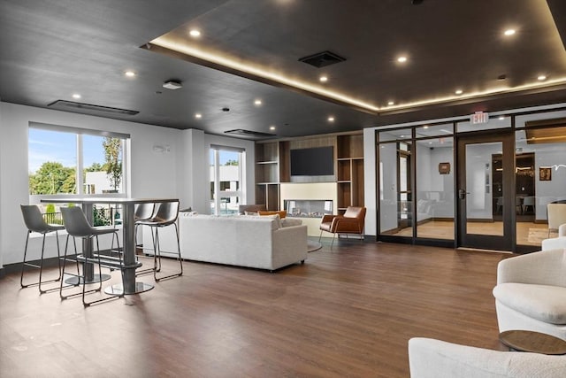 living room featuring a tray ceiling and dark wood-type flooring