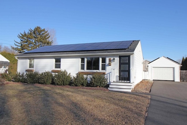 view of front of house with an outbuilding, a front yard, aphalt driveway, solar panels, and a detached garage