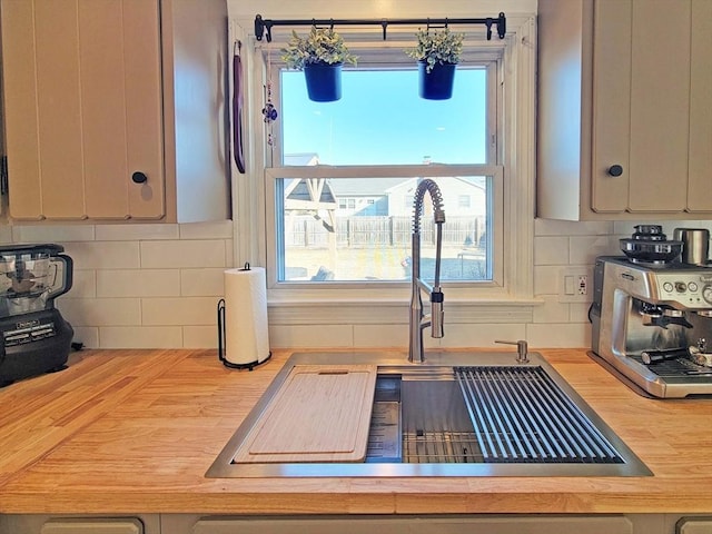 kitchen featuring wooden counters, backsplash, and a sink