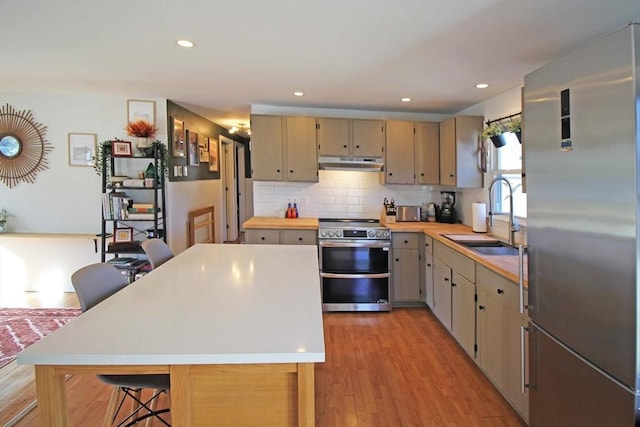 kitchen featuring a sink, stainless steel appliances, under cabinet range hood, and light countertops