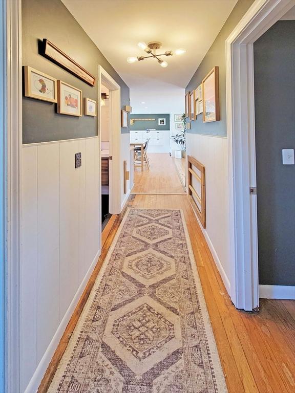 corridor with light wood-style flooring and wainscoting