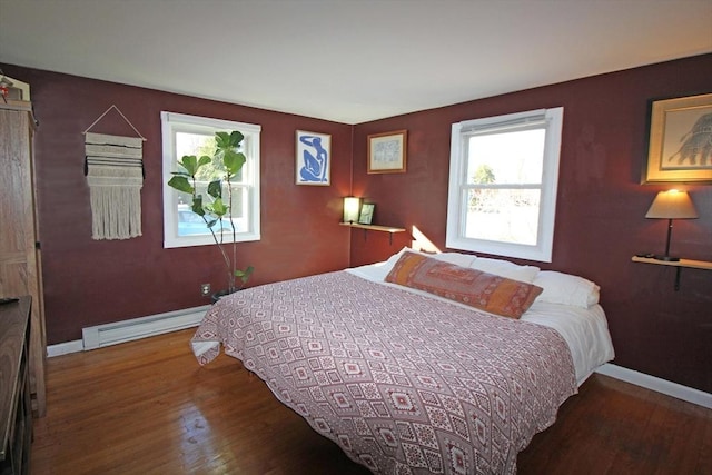 bedroom featuring a baseboard heating unit, baseboards, and wood finished floors