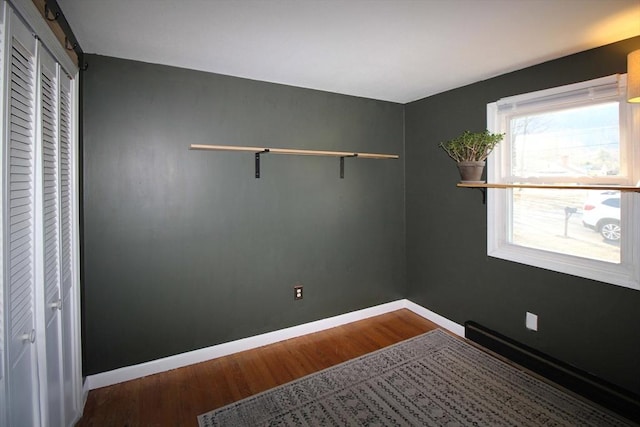 unfurnished room featuring a barn door, baseboards, and wood finished floors