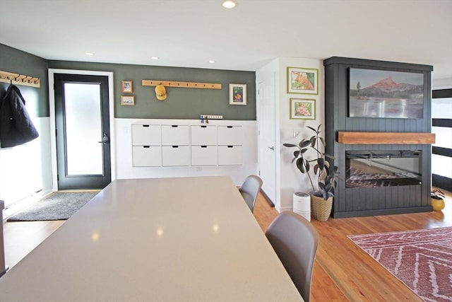 dining area with a glass covered fireplace, recessed lighting, and wood finished floors