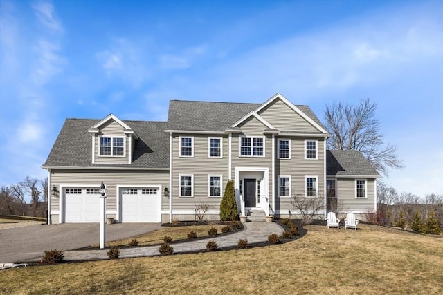 colonial house with entry steps, a front yard, driveway, and roof with shingles