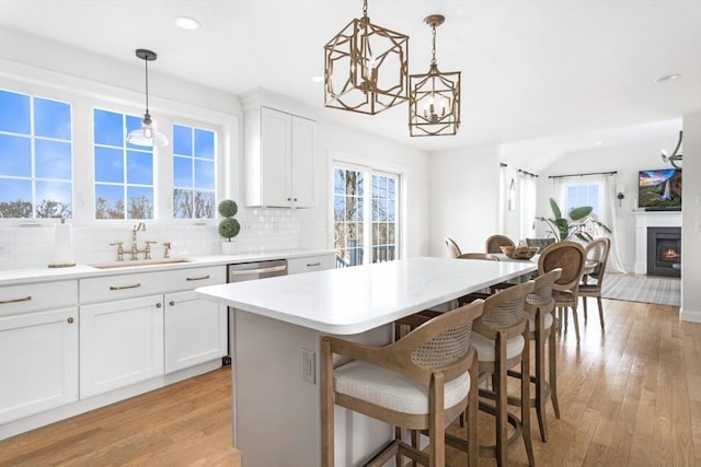 kitchen featuring a notable chandelier, a breakfast bar, a sink, decorative backsplash, and a healthy amount of sunlight